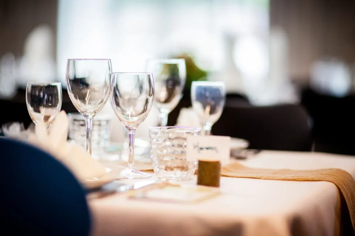 Elegant table setting with wine glasses and decor in softened light, perfect for formal dining or weddings.